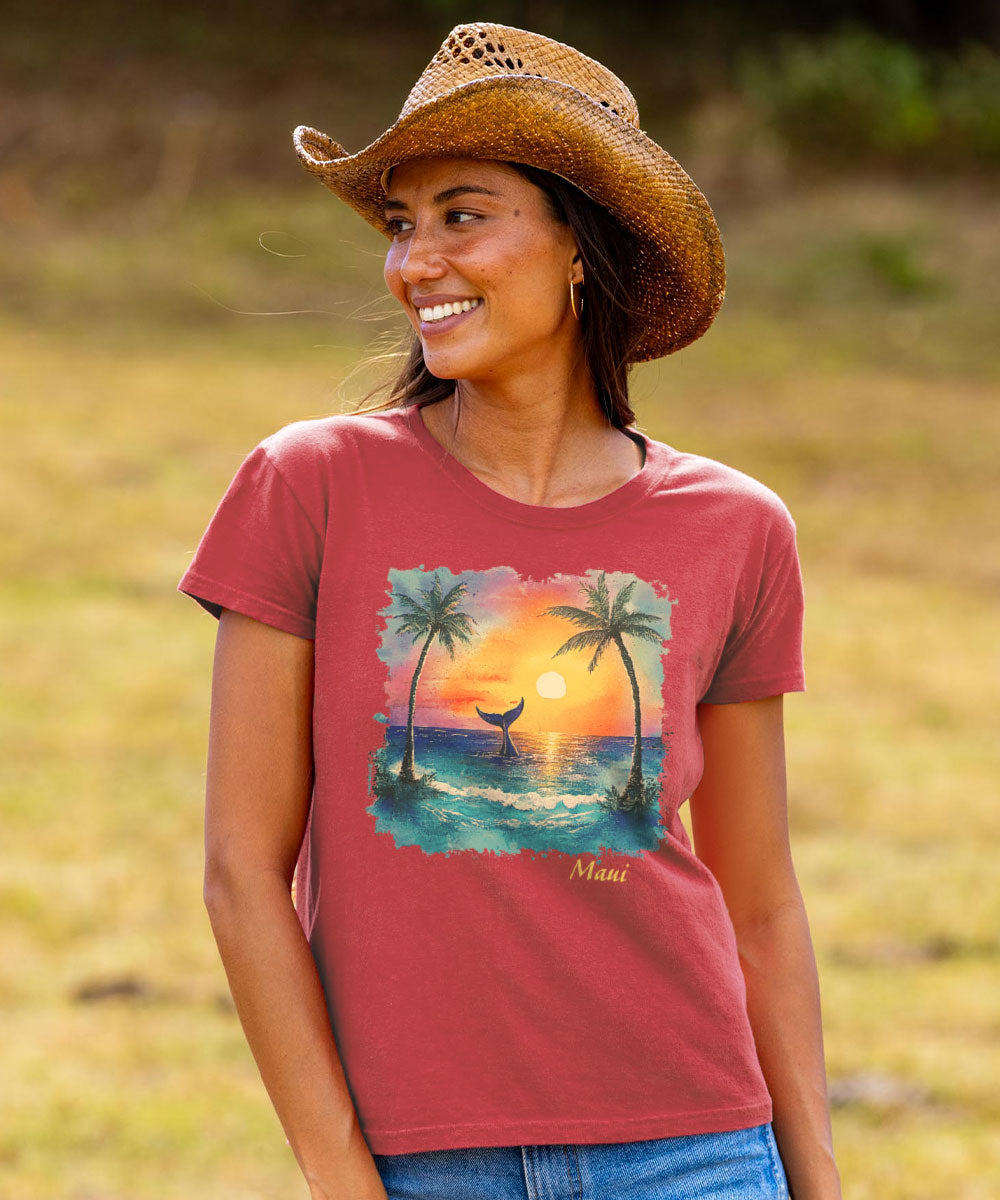 Woman wearing a red t-shirt with a sunset and palm tree design, standing in a field. View 2