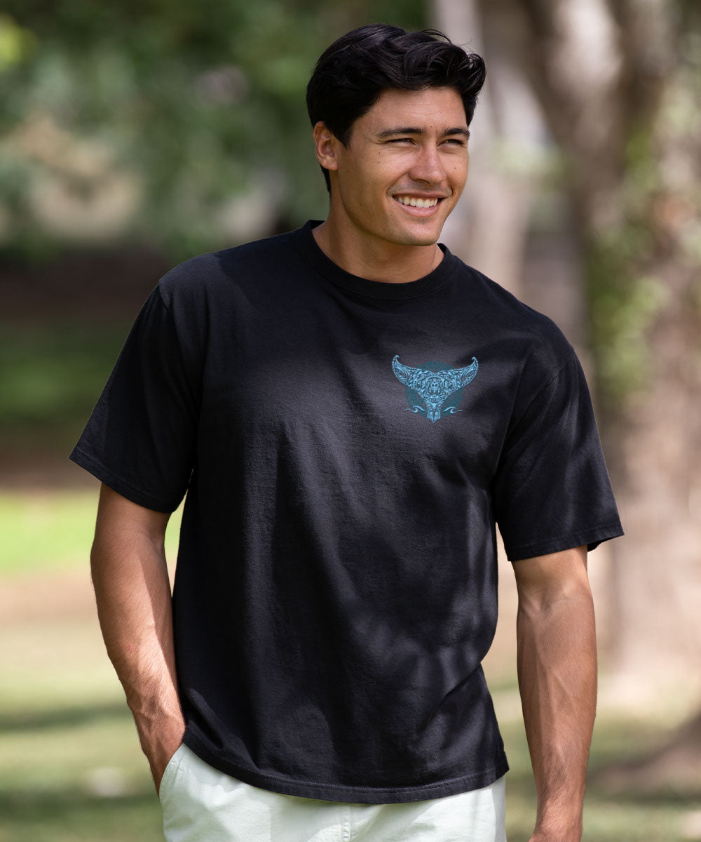 Man wearing a black t-shirt with a blue graphic logo, standing outdoors. View 3