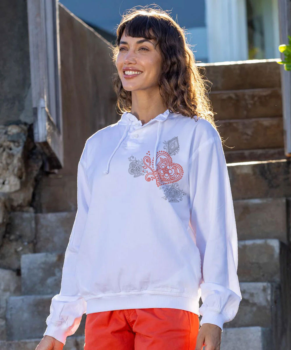 Woman wearing a white hoodie with red and black designs, standing outdoors. View 2