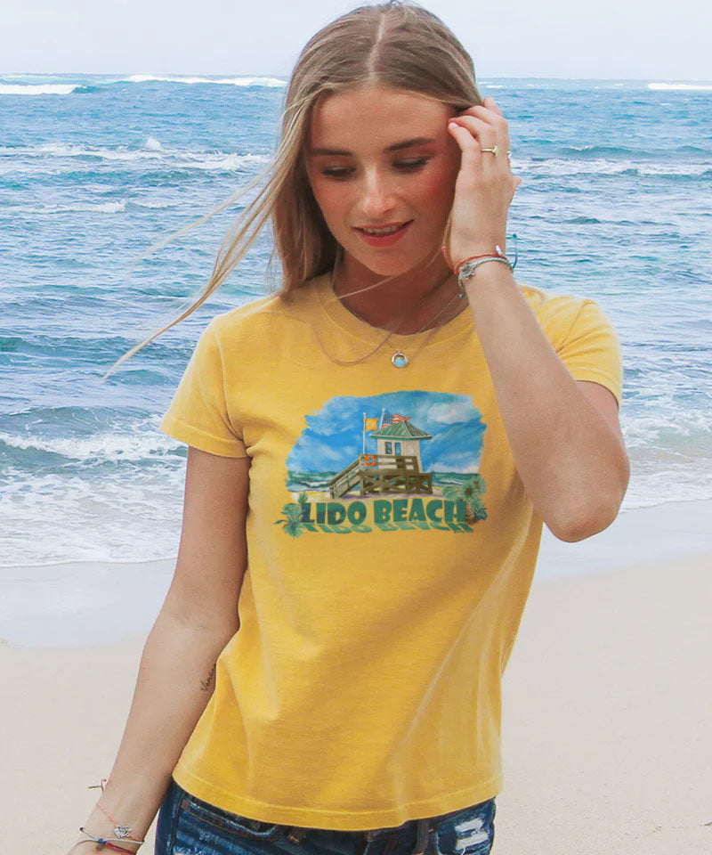 Woman wearing a yellow t-shirt with 'Lido Beach' design on a beach View 2