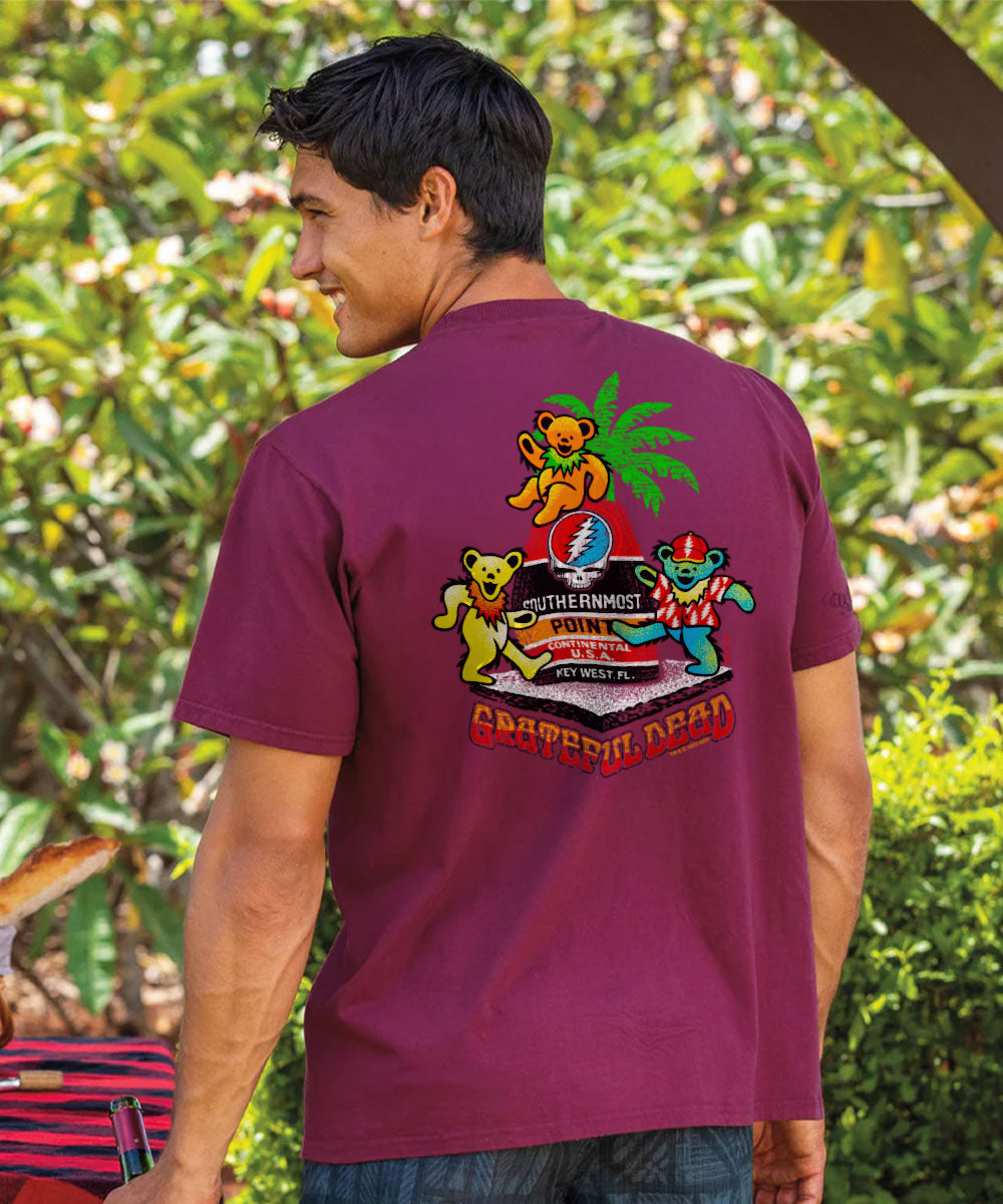 Man wearing a maroon t-shirt with a colorful graphic design, standing outdoors. View 2