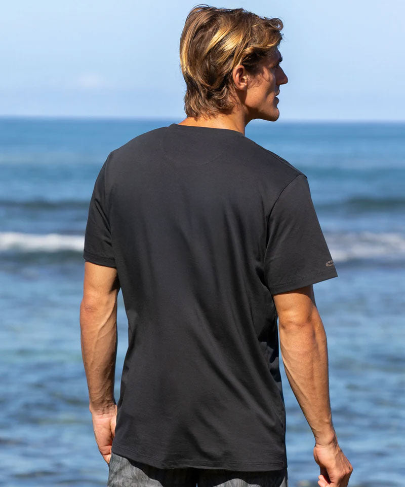 Man wearing a black t-shirt standing on a beach with ocean in the background View 3