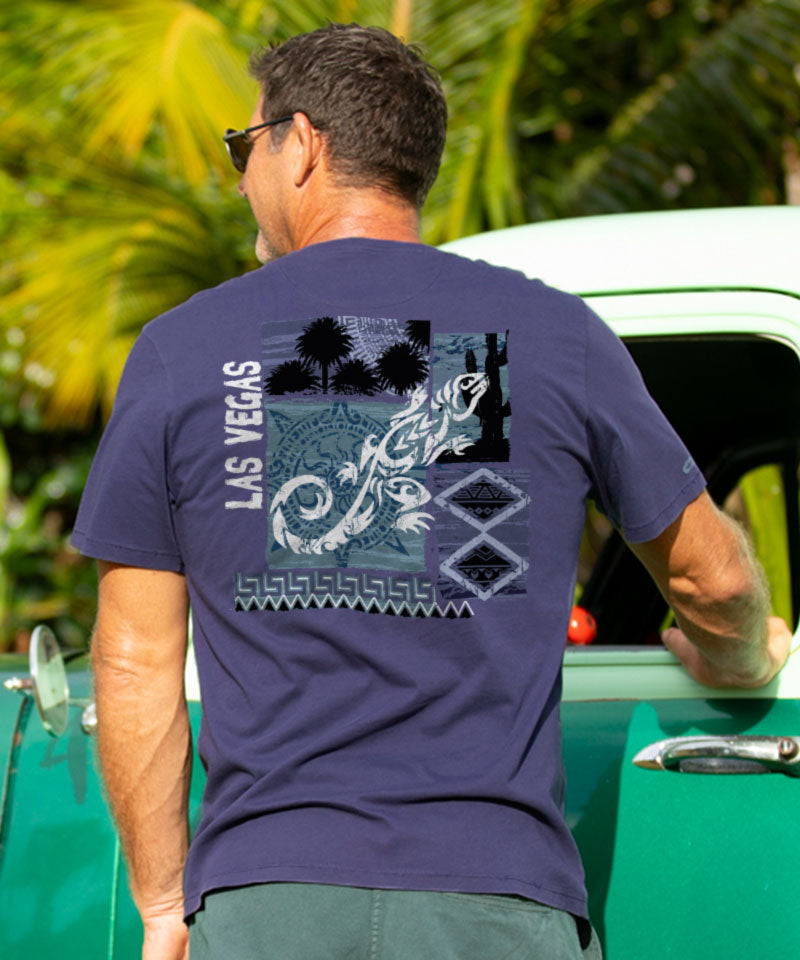 Man wearing a indigo t-shirt with a graphic design and 'Las Vegas' text, standing next to a green vintage car. View 2