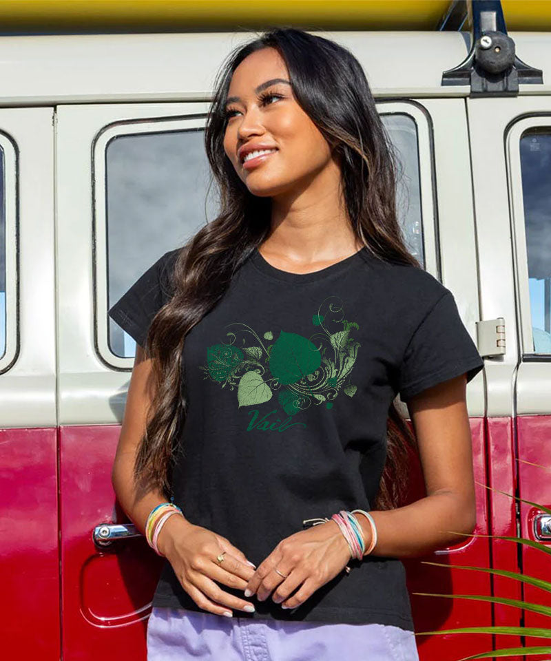 Woman wearing a black t-shirt with green design in front of a red and white van. View 2