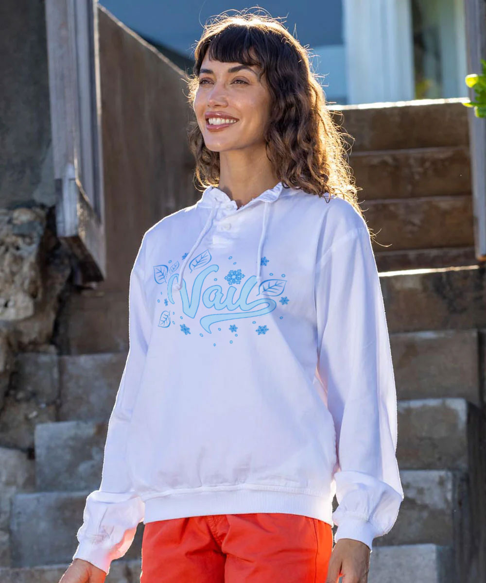 Woman wearing a white hoodie with blue text and red pants standing on steps. View 2