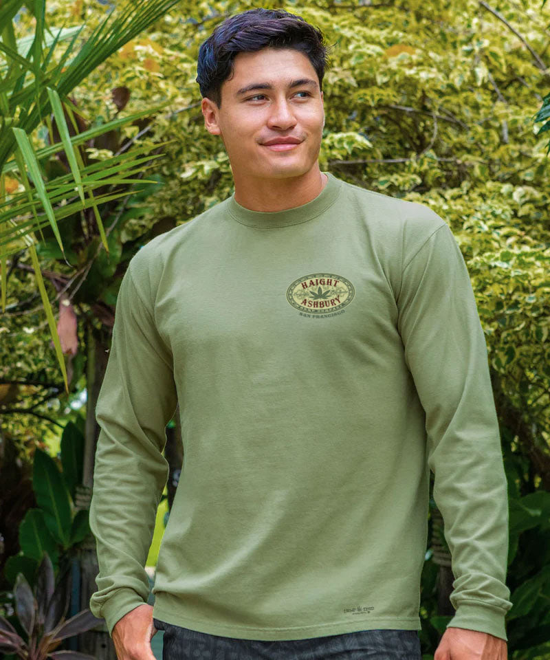 Man wearing a green long-sleeve shirt with a logo in a forest setting View 3