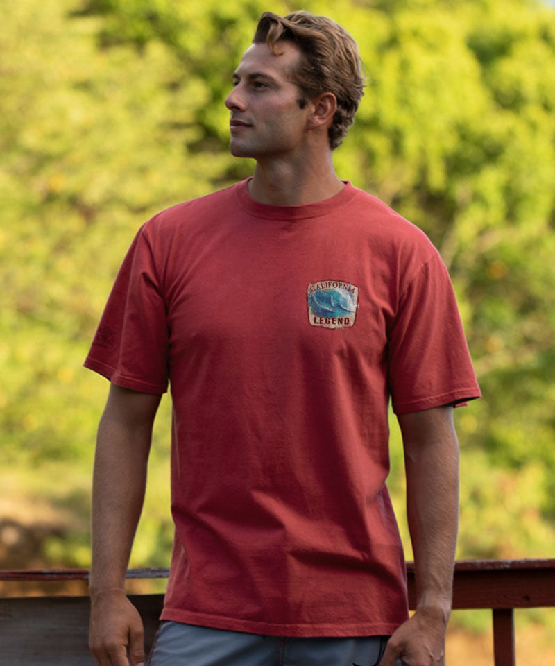 Man wearing a red t-shirt with a logo, standing outdoors View 3