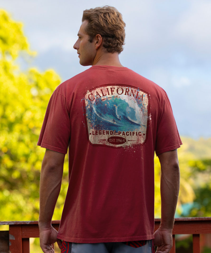Man wearing a red t-shirt with a 'California Legend Pacific' graphic, standing outdoors with greenery in the background. View 2