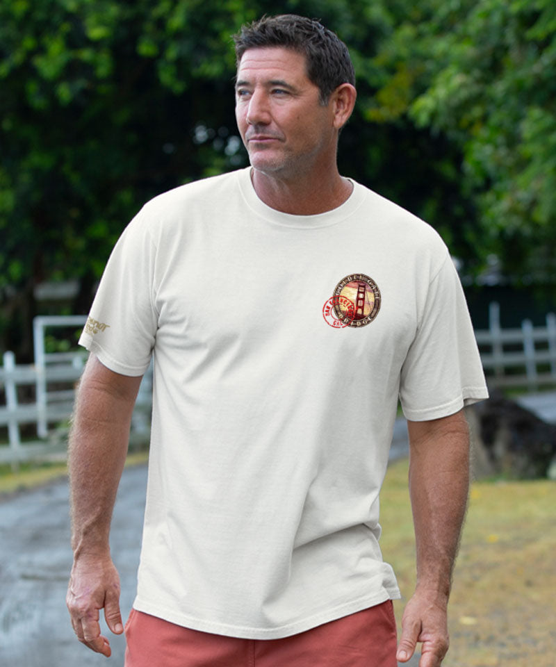 Man wearing a creamy white t-shirt with a logo, standing outdoors View 3