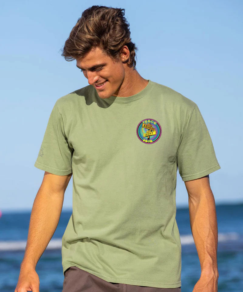 Man wearing a green t-shirt with a colorful logo, standing on a beach View 3