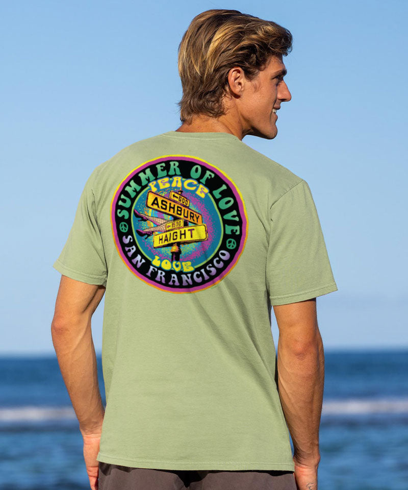 Man wearing a green t-shirt with a graphic design on the back, standing in front of the ocean View 2