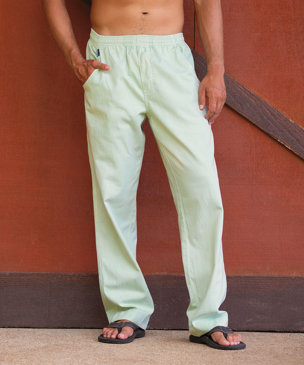 Man wearing light green pants against a red wall.