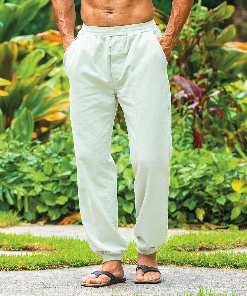 Man wearing light-green pants standing outdoors with greenery in the background