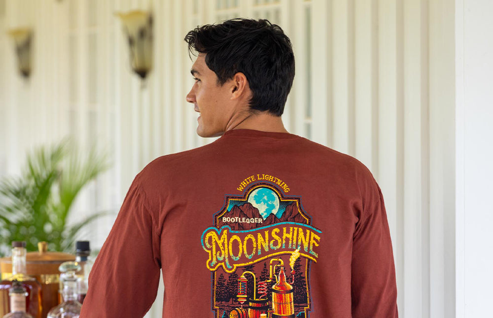 Man wearing a red long-sleeve shirt with 'Moonshine' graphic design indoors.
