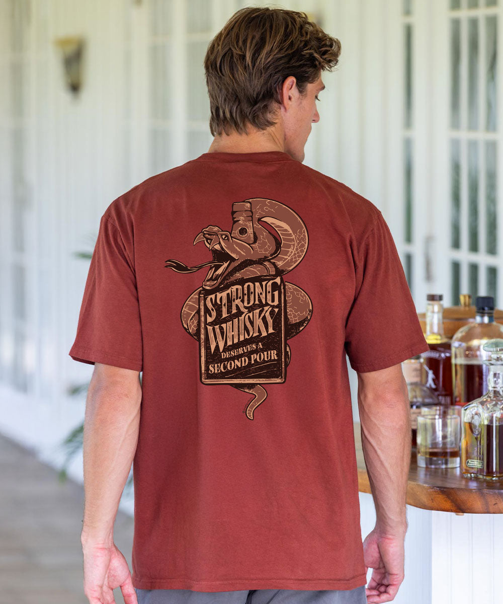 Man wearing a brown t-shirt with 'Strong Whisky' design, standing in a room with bottles in the background. View 2