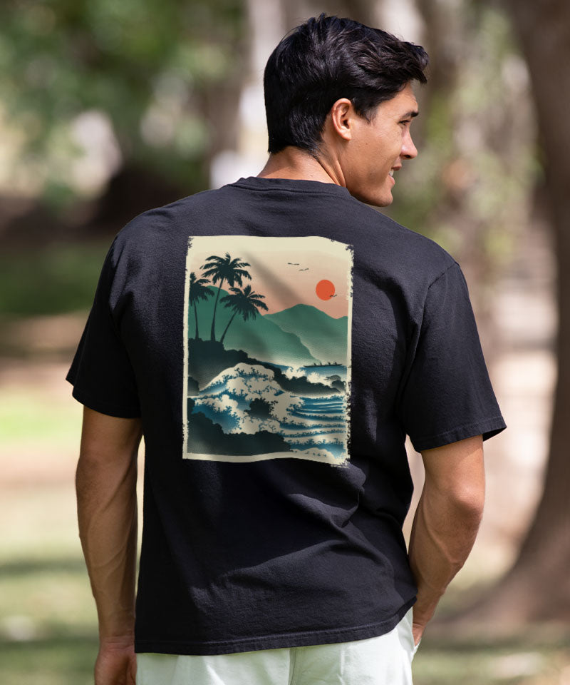 Man wearing a black t-shirt with a tropical graphic on the back, standing outdoors. View 2