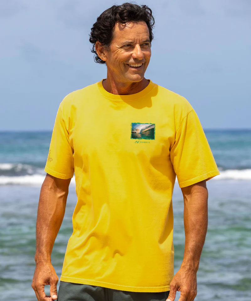 Man wearing a yellow t-shirt with a logo on a beach View 3