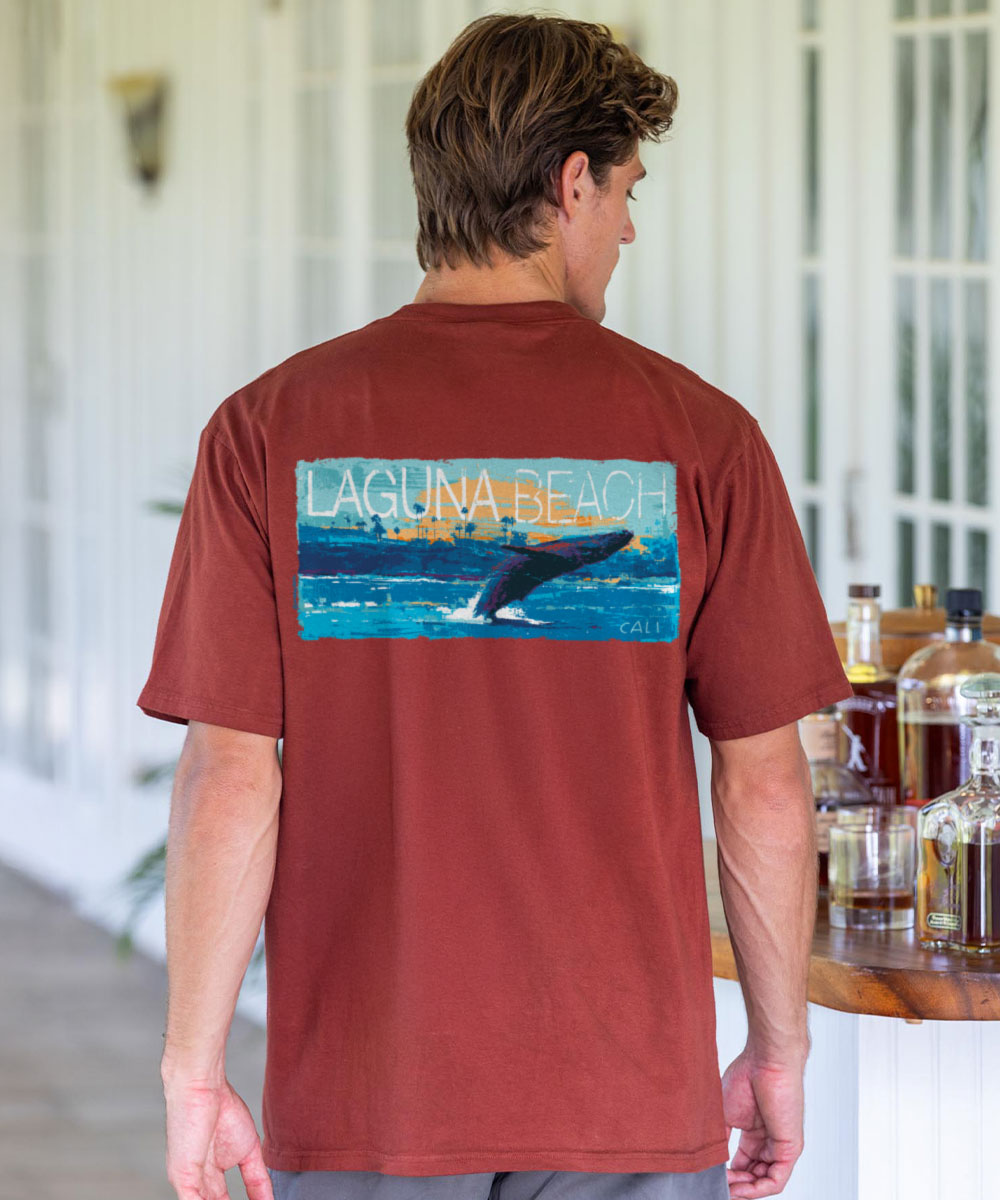 Man wearing a red t-shirt with a graphic of a whale and 'Laguna Beach' text, standing in a casual setting. View 2