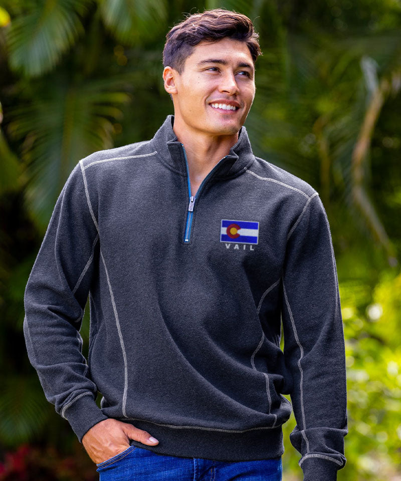 Man wearing a dark gray pullover with a Vail, Colorado flag logo, standing outdoors. View 2