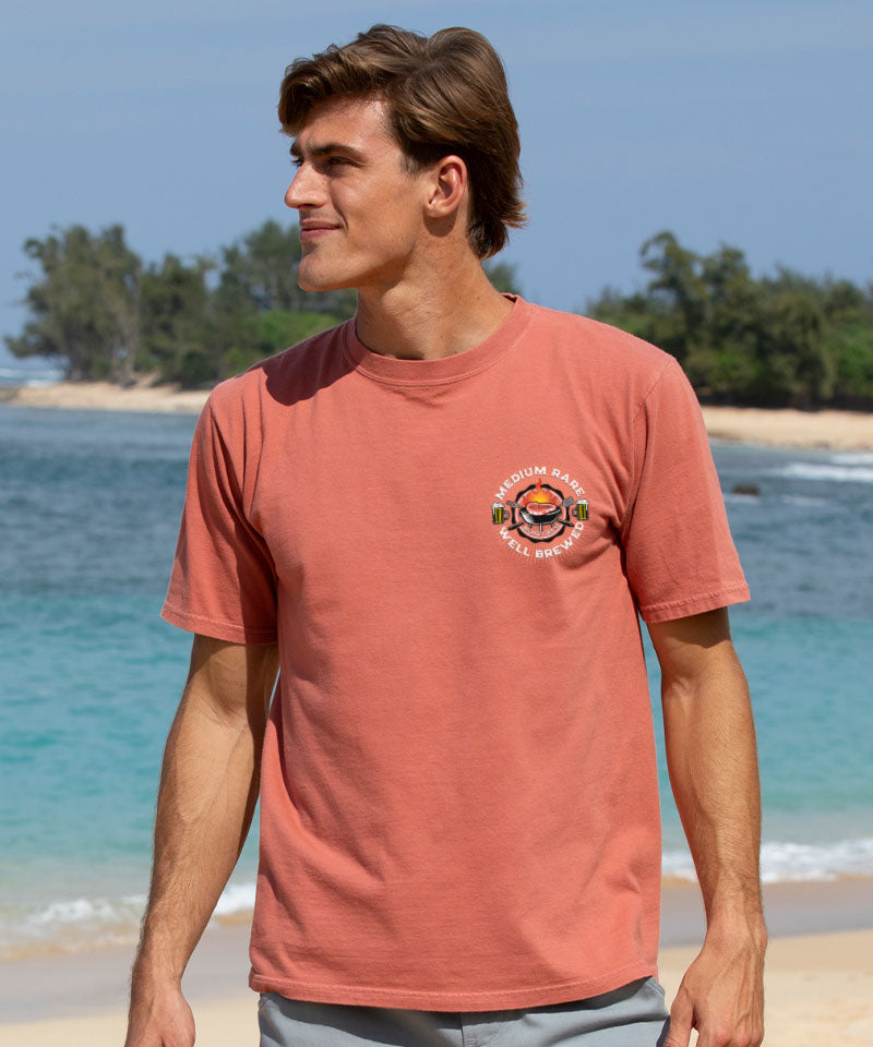 Man wearing a red t-shirt with a logo on a beach View 3