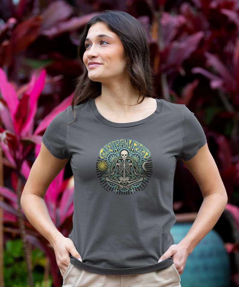 Woman wearing a gray t-shirt with a graphic design in front of pink and green plants View 2