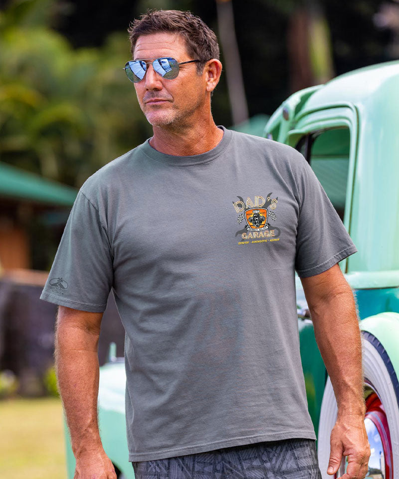 Man wearing a gray t-shirt with a logo in front of a vintage car View 3
