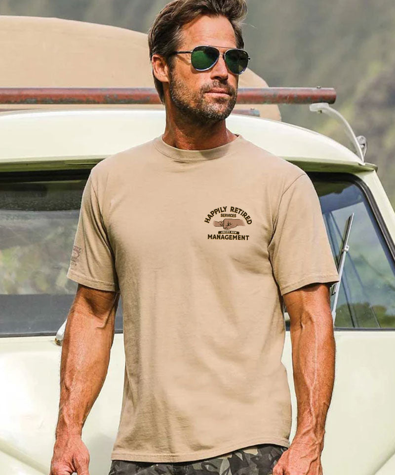 Man wearing a beige t-shirt with text standing next to a vintage vehicle. View 3