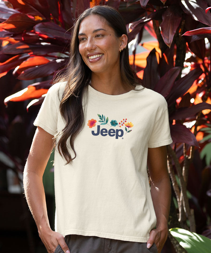 Woman wearing a white Jeep t-shirt standing in front of leafy plants View 3
