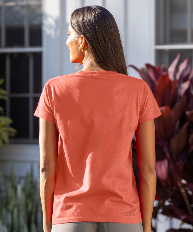 Woman wearing a coral t-shirt standing outdoors with plants in the background View 3