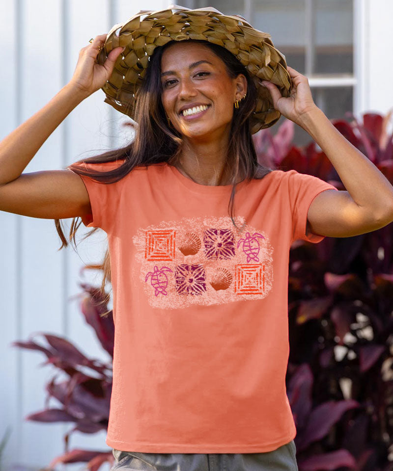 Woman wearing a coral shirt with a tropical deign on it wearing a tropical hat View 2