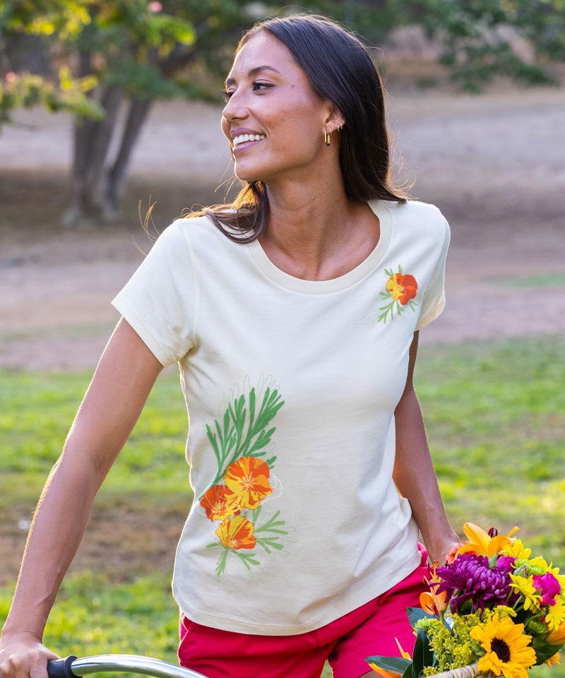 Woman wearing  a tan t-shirt with a floral deign on it holding the handlebars of a bike View 2