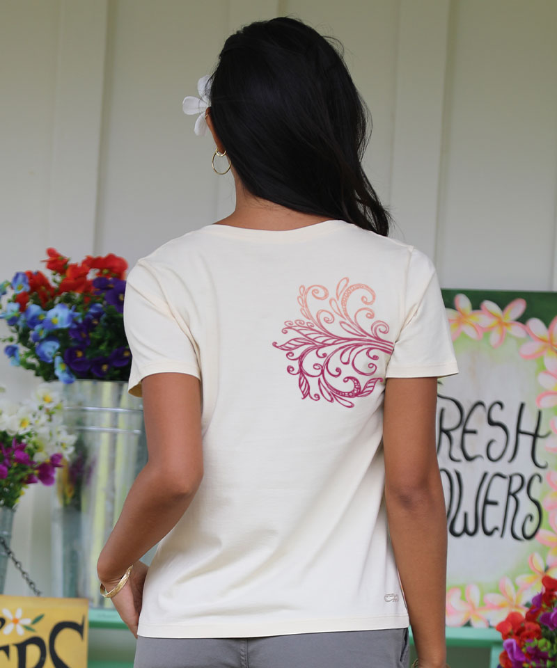 Woman wearing a tan shirt with a floral deign on the back standing in front of a white wall View 3