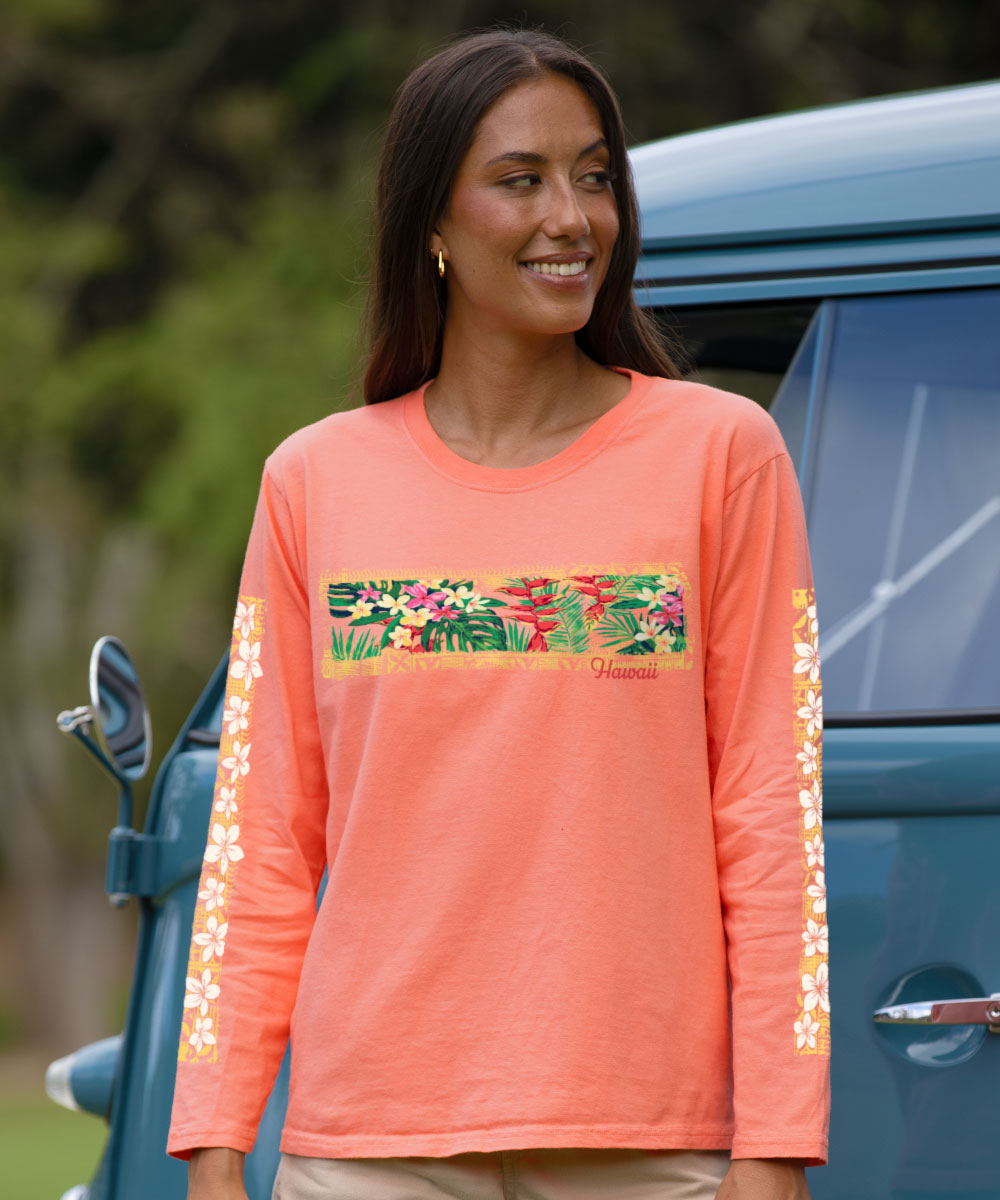 Woman wearing a coral long-sleeve shirt with floral design standing next to a blue vehicle.