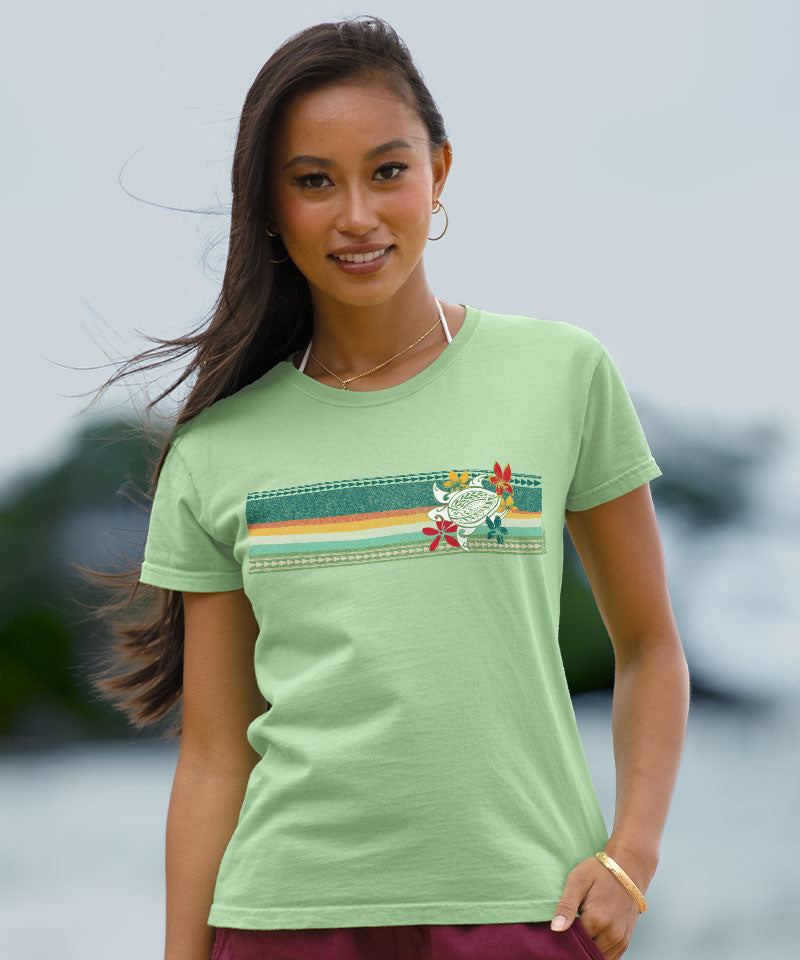 Woman wearing a light green t-shirt with a colorful graphic design outdoors. View 2