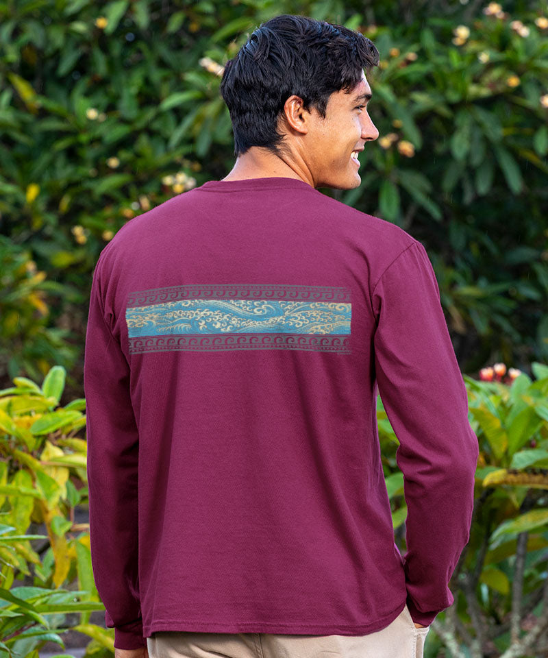 Man wearing a maroon long-sleeve shirt with a decorative back design, standing in front of green foliage. View 3