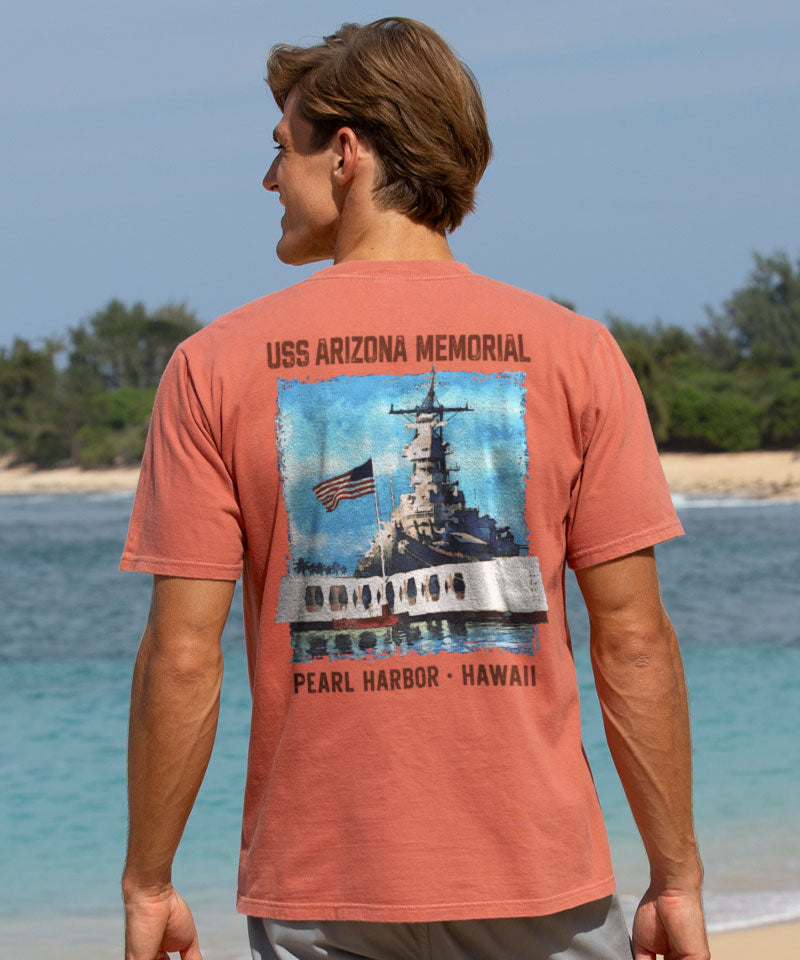 Person wearing a t-shirt with USS Arizona Memorial design by a beach. View 2
