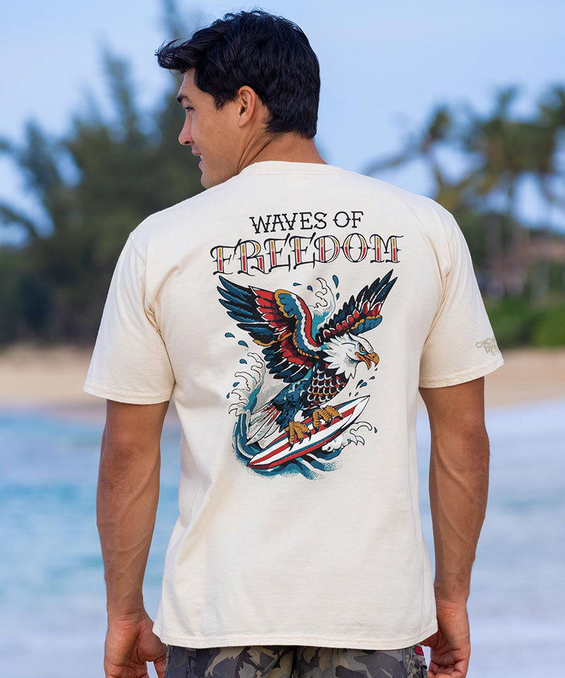 Man wearing a t-shirt with 'Waves of Freedom' design on a beach View 2