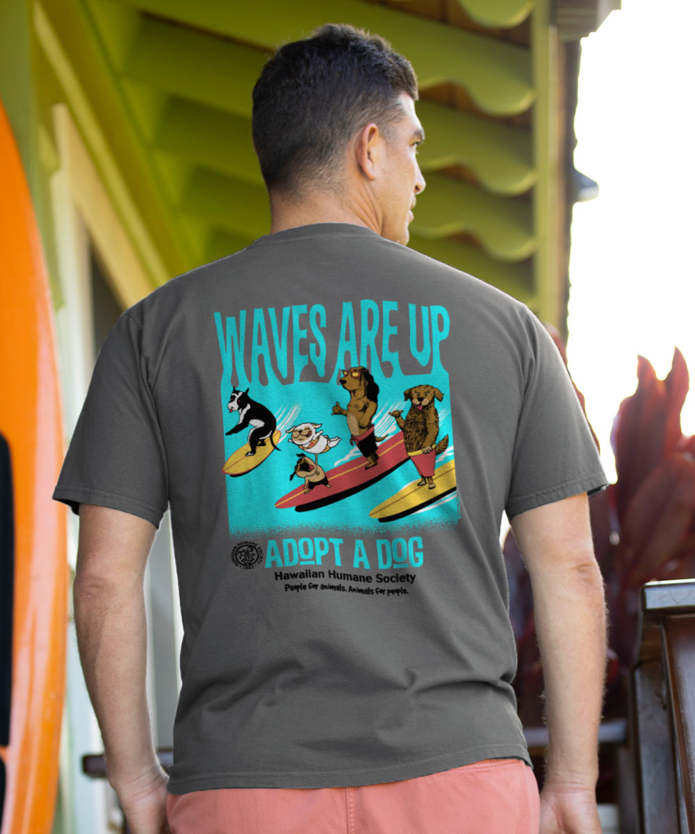 Person wearing a t-shirt with 'Waves Are Up Adopt A Dog' design outdoors.