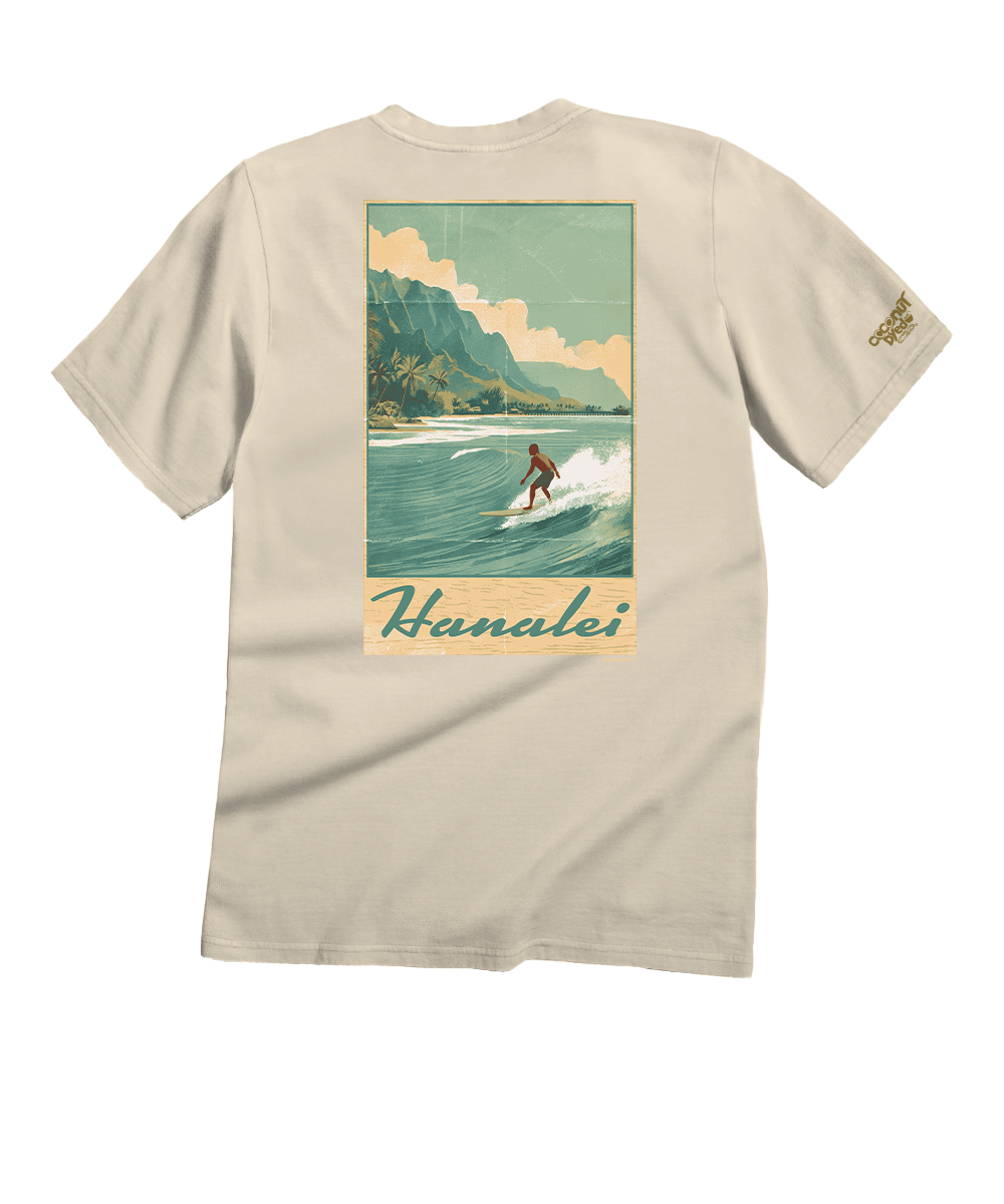A beige short-sleeve t-shirt shown from the back, featuring a large vintage-style graphic print of a surfer in Hanalei, Hawaii, with a small gold embroidered logo on the left sleeve. View 1