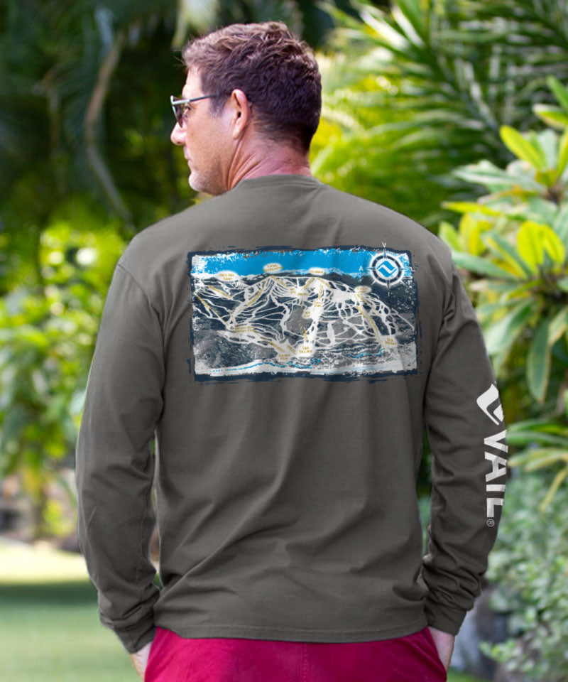 Man wearing a green long-sleeve shirt with a graphic design on the back, standing in a garden. View 2