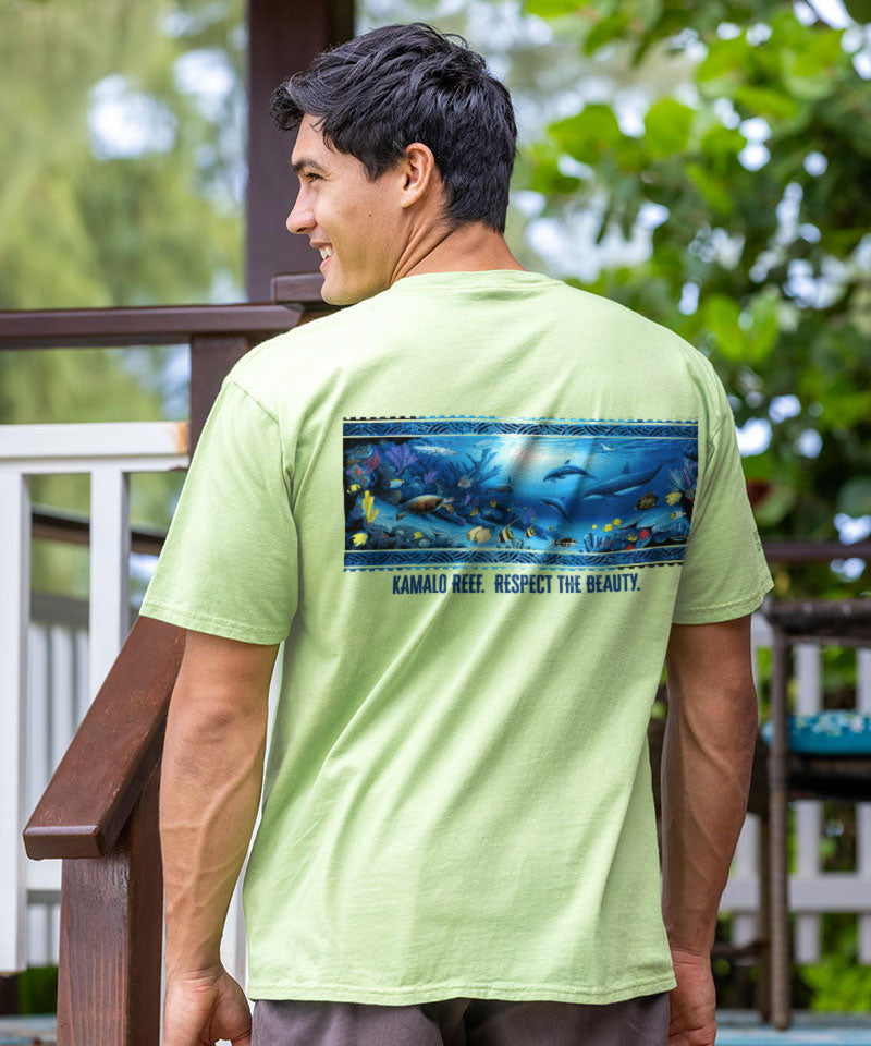 Man wearing a light green t-shirt with an underwater scene and text on the back, standing outdoors.