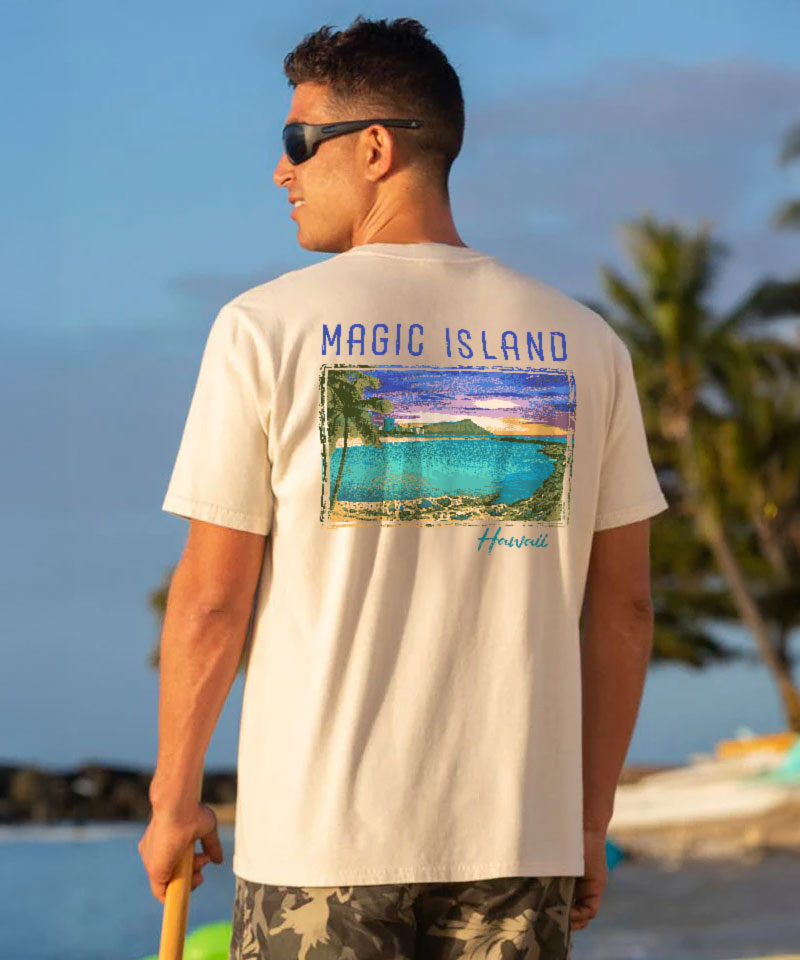Man wearing a creamy white t-shirt with a graphic design, standing on a beach View 2