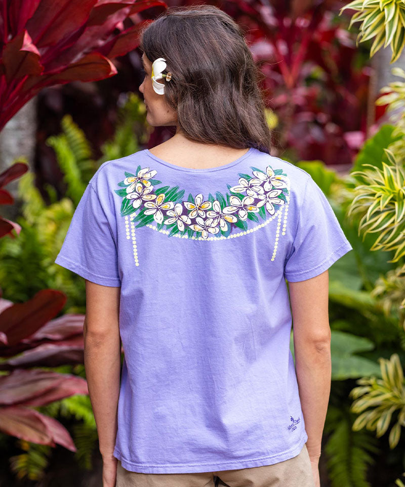 Woman wearing a purple t-shirt with floral design in front of foliage View 3