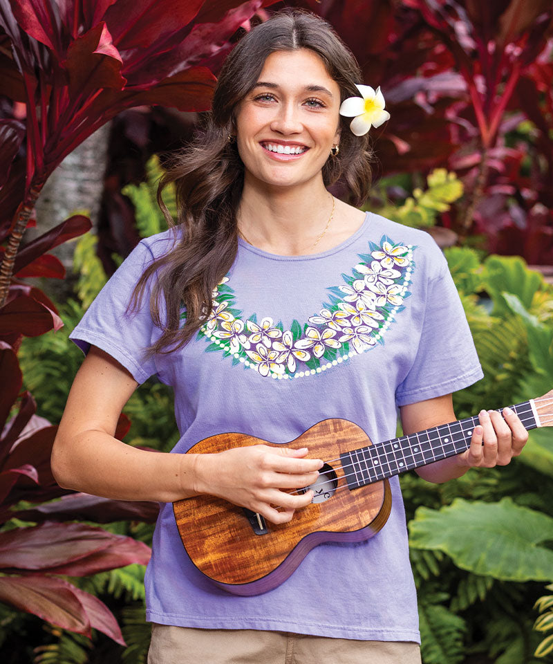 Woman wearing a light blue blouse with floral design playing an ukulele View 2