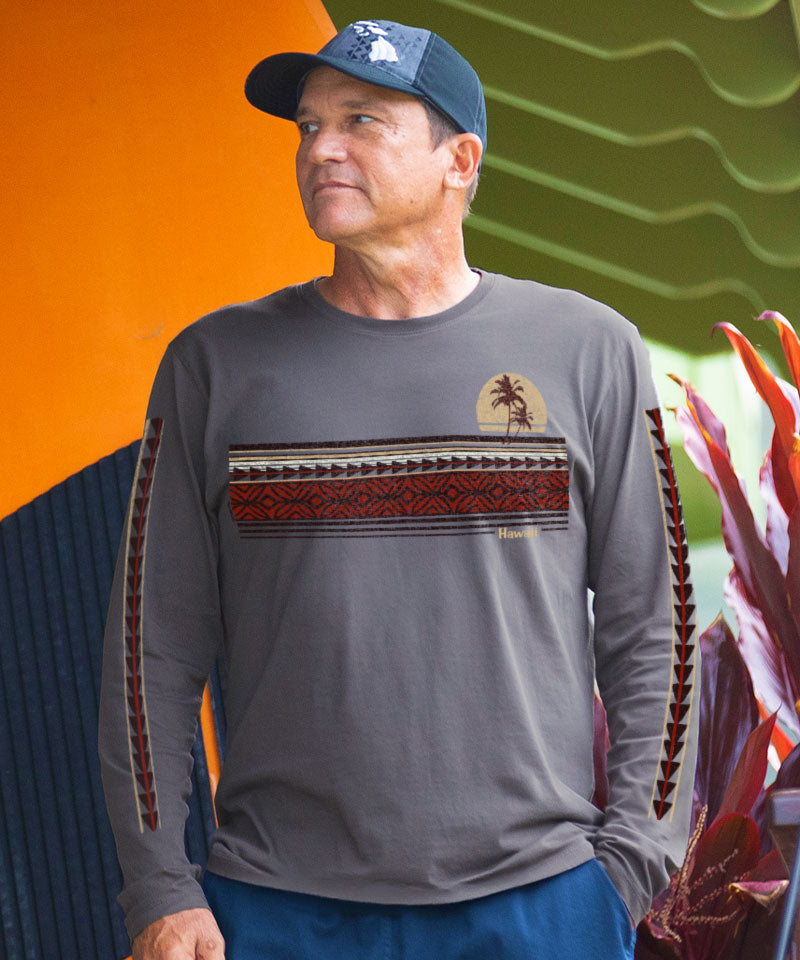 Man wearing a long-sleeve shirt with a design and cap, standing against a colorful background. View 2