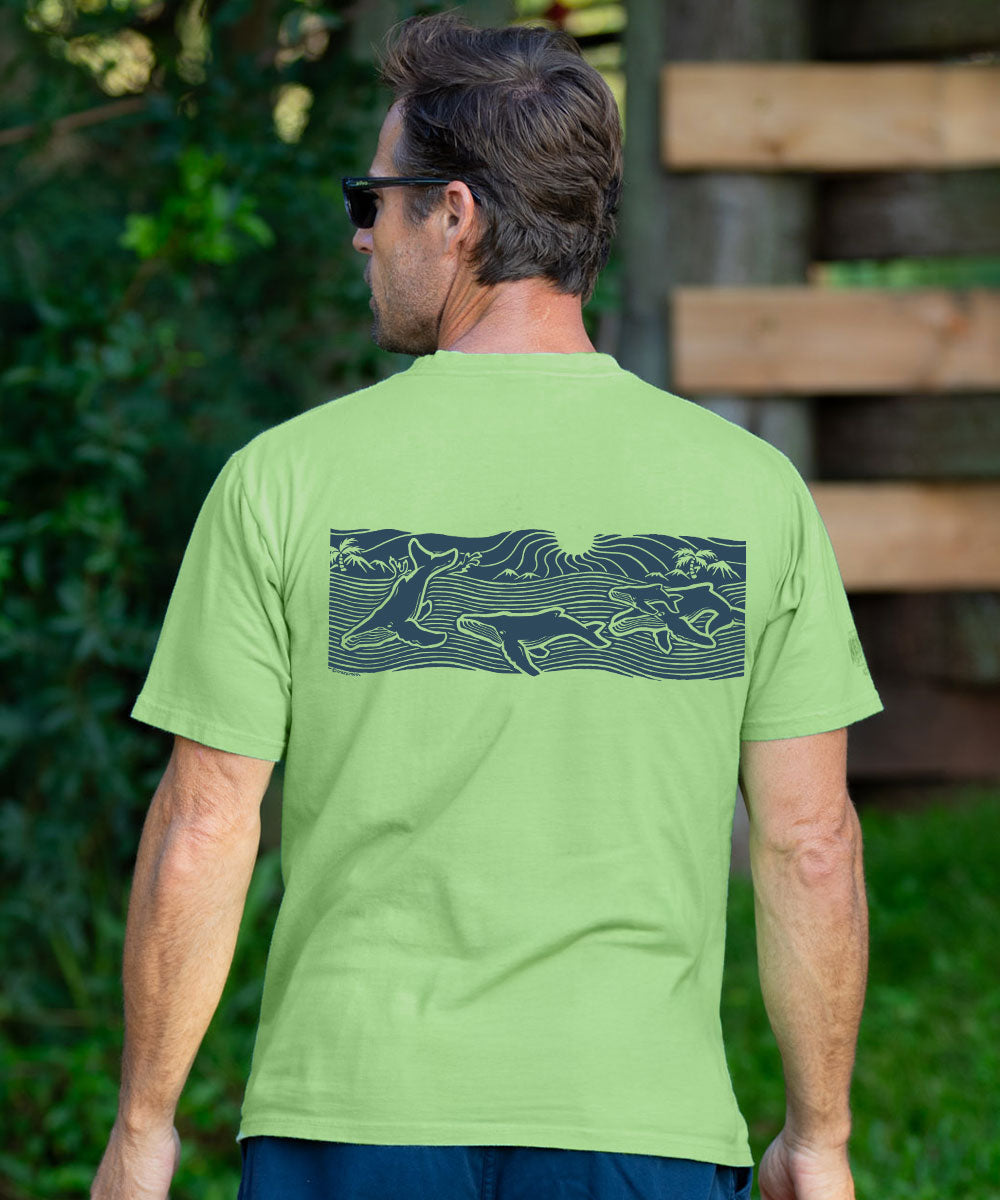 A man wearing a light green t-shirt with a dark graphic print of dolphins on the back, photographed from behind in an outdoor setting. View 3