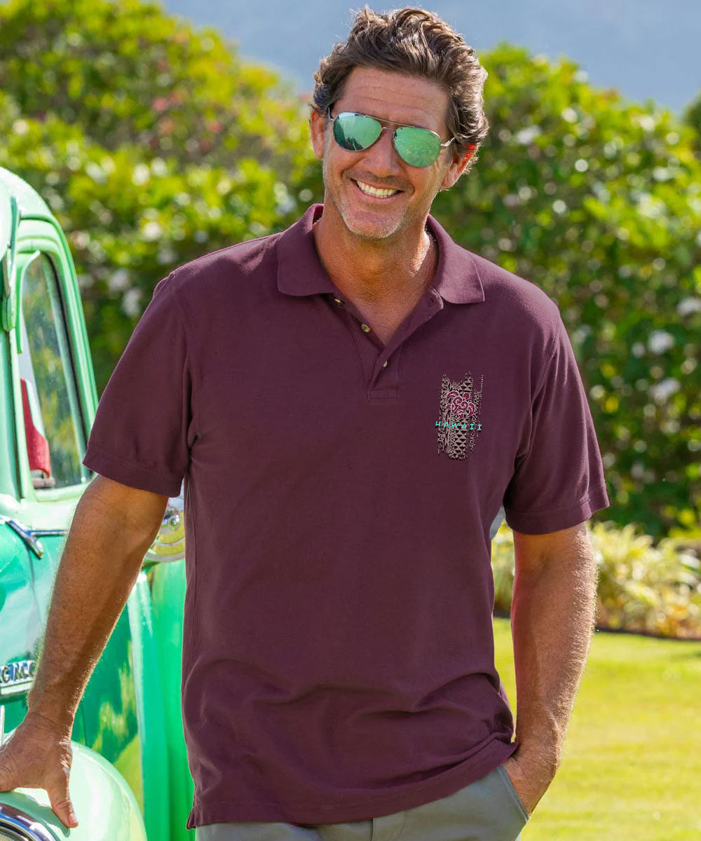 A man wearing a short-sleeve polo shirt in deep burgundy with a small embroidered logo on the left chest, standing outdoors next to a green vintage car with a blurred garden background. View 2