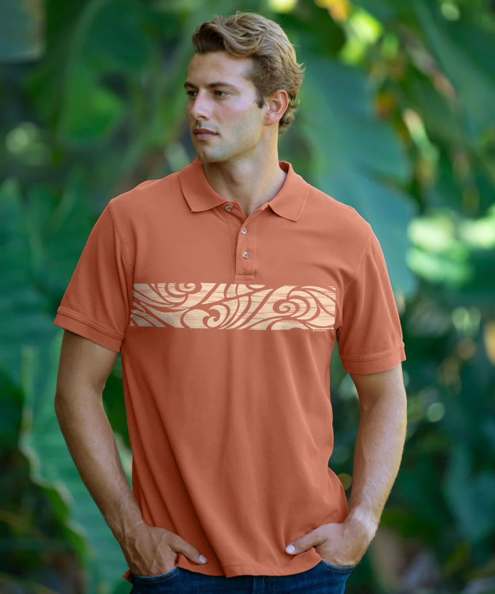 A man wearing a short-sleeve polo shirt in a terracotta orange color, featuring a small embroidered patterned logo on the left chest, posed against a blurred background of green tropical foliage. View 2