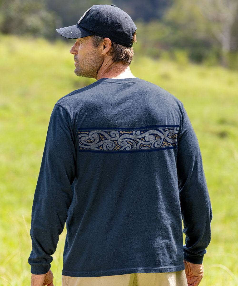 A man wearing a navy blue long-sleeve shirt with a decorative paisley pattern band across the upper back, standing in a grassy outdoor field. View 3