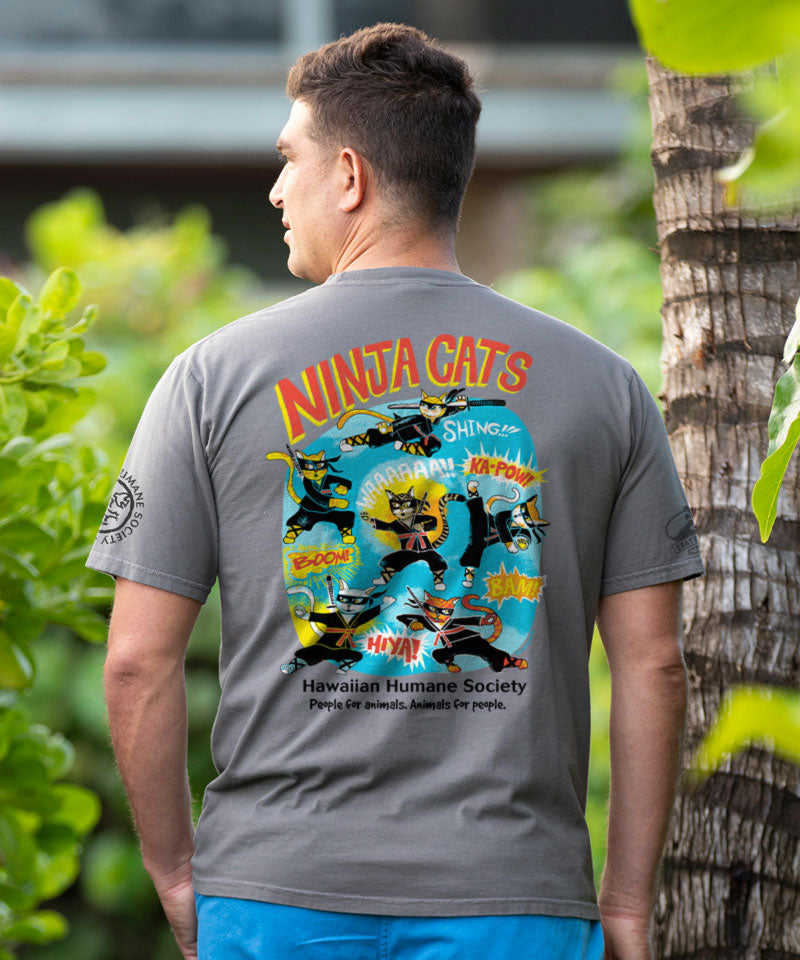 Man wearing a gray t-shirt with 'Ninja Cats' design, standing outdoors with greenery in the background. View 2